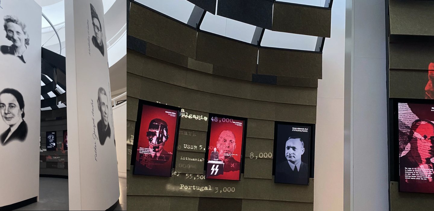 The installation in the atrium. Pillars printed with portraits of victims stand near a curved wall of vertical screens showing the conference participants, with country names and numbers projected between them.
